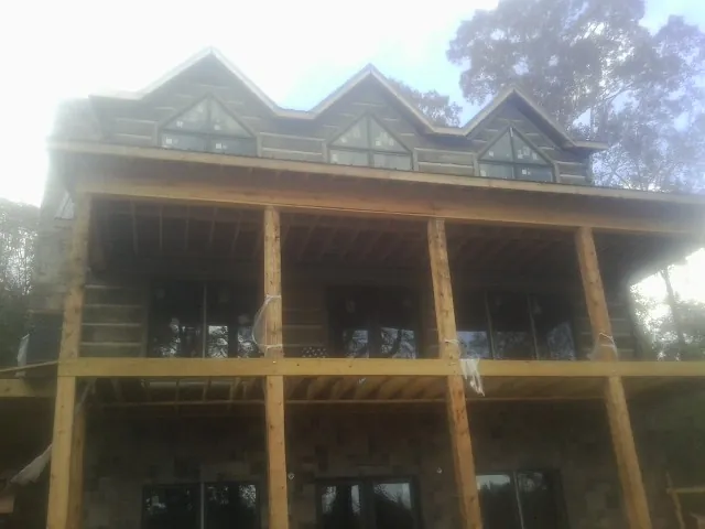 Dormers and porch framing on a large log home under construction — Roof Coating work by our crew in Sturbridge