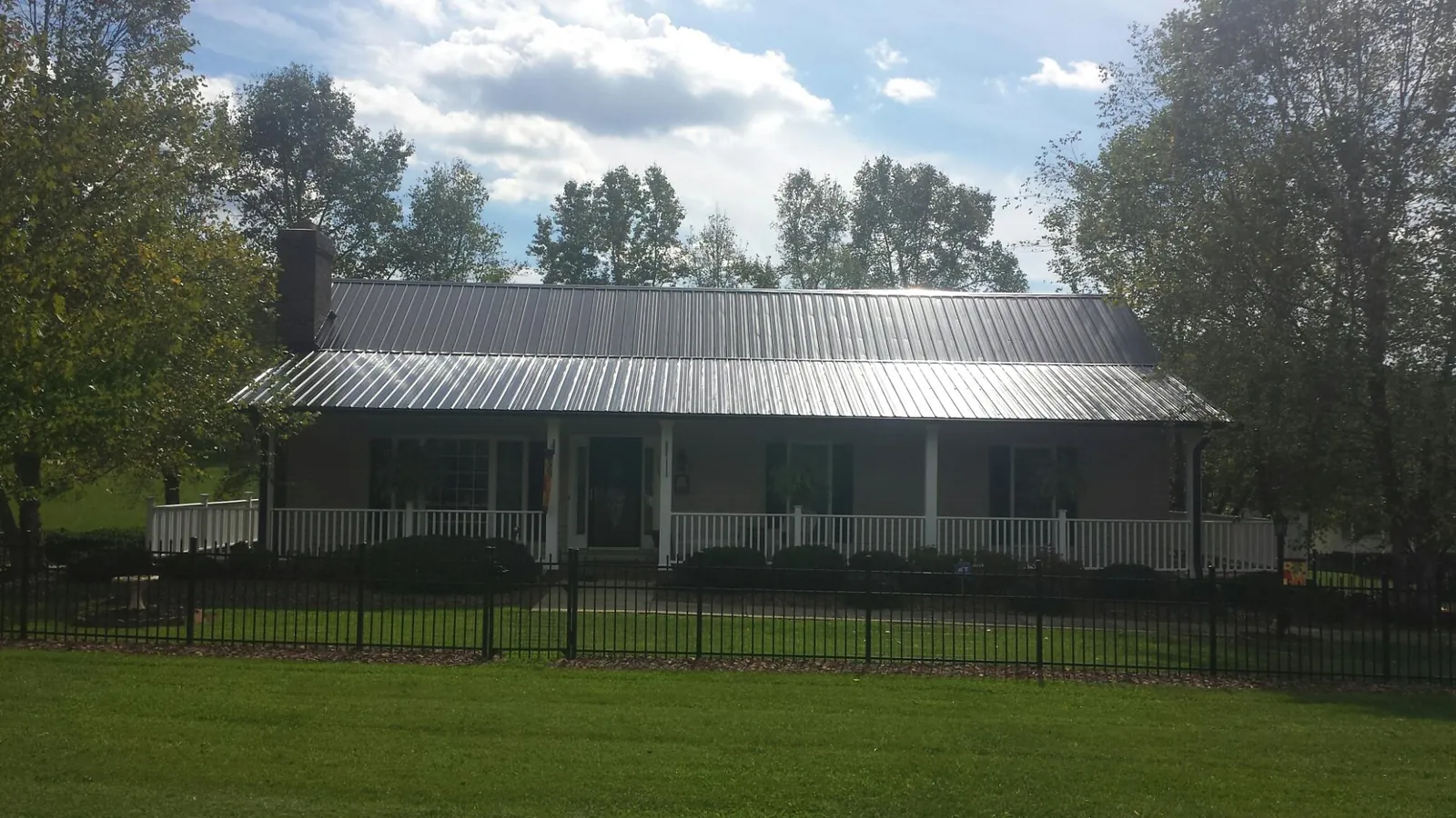 Gray metal roof on a brick ranch with a full width front porch — Gutter Guard Installation work by our crew in Sturbridge
